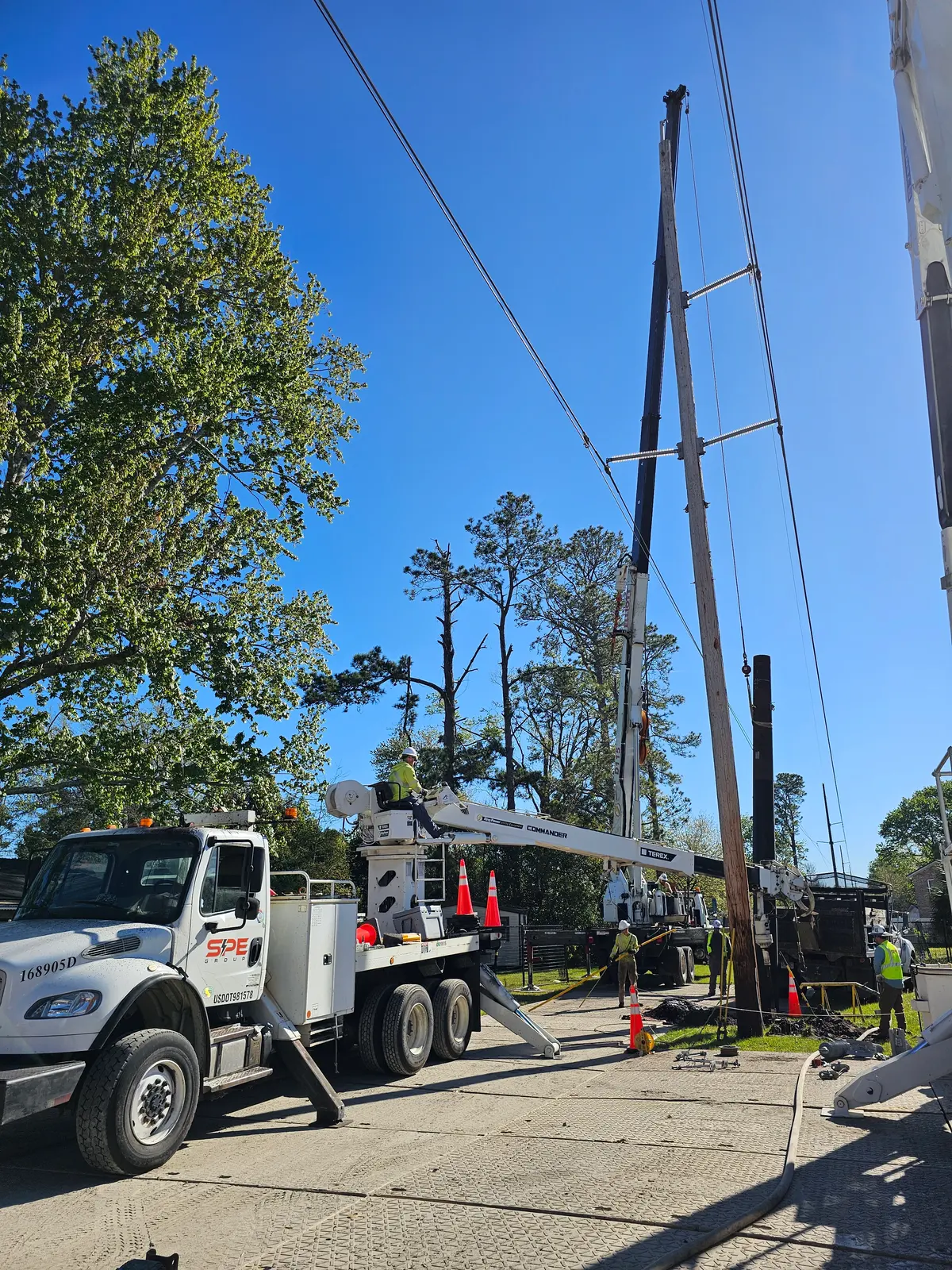 SPE digger derrick and crew setting a utility pole