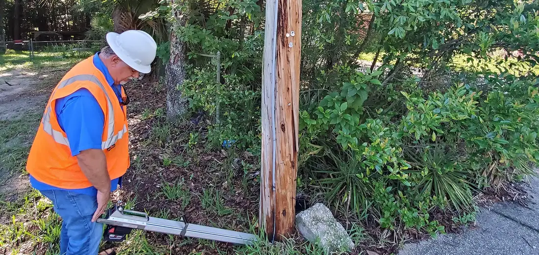 SPE inspector in full PPE checking a distribution pole