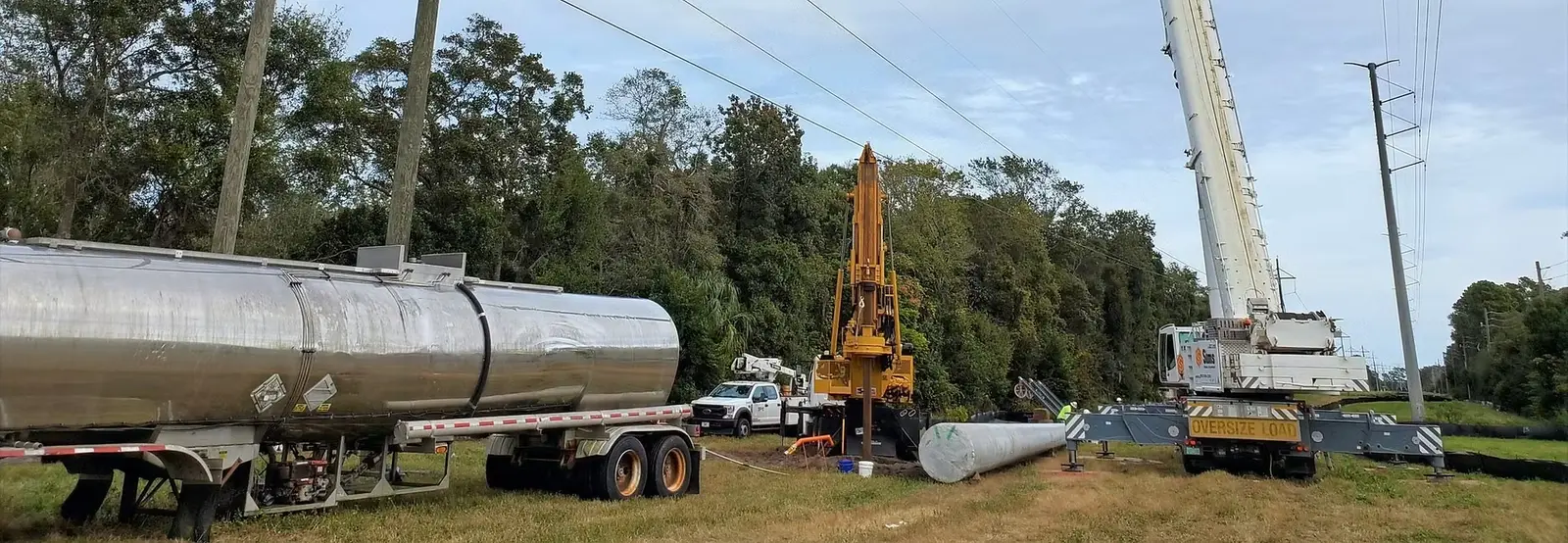 Drill rig, crane, and tanker staged at a transmission structure site