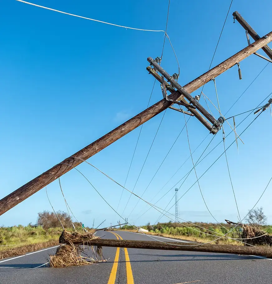 Storm-snapped poles and downed conductor across a roadway